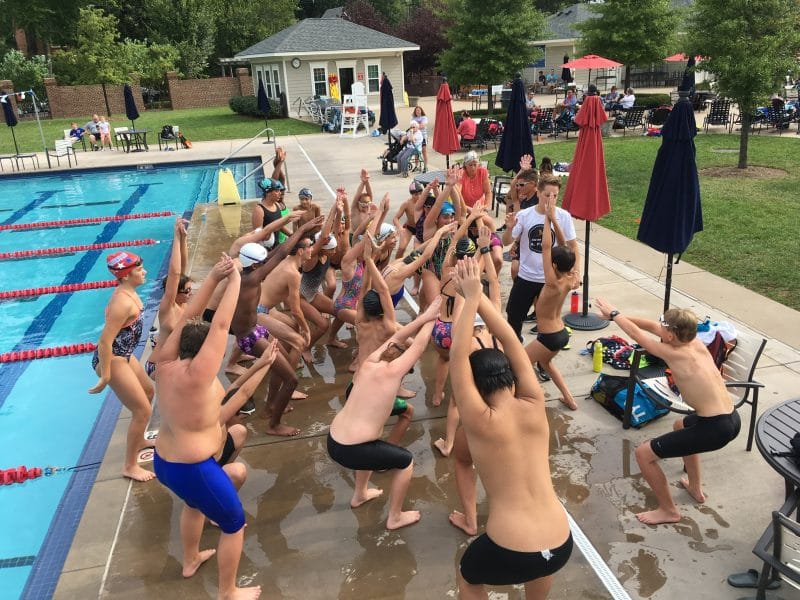 Young swimmers doing dryland exercises and warmup before swimming.