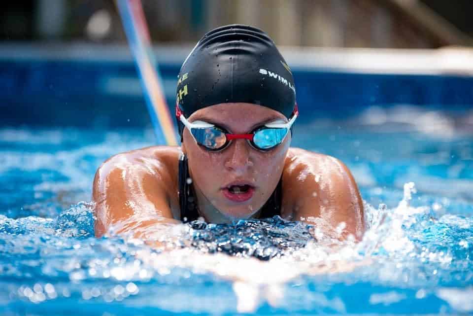 Swimmer in a pool wearing a swim cap and goggles.