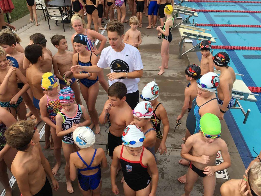 Abbie Fish surrounded by kids during swim camp.