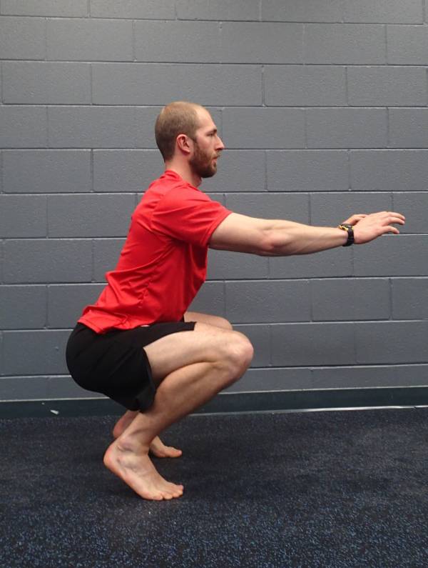 A trainer demonstrating an incorrect way of doing squats.