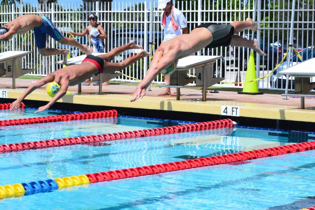 Swimmers jumping in the pool at a swimming age group local competition.
