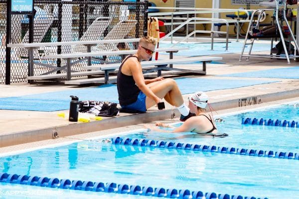 Abbie coaching a swimmer at an outdoor swimming pool.